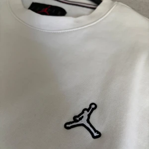 Vit sweatshirt från Jordan - Säljer en stilren vit sweatshirt från Jordan med det klassiska Jumpman-loggan broderad på bröstet. Tröjan har rund halsringning och långa ärmar. Perfekt för en sportig och avslappnad look. Köpt för 700kr