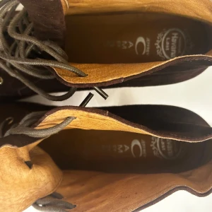 Bruna mockaboots med snörning och klack - Säljer ett par bruna boots i mocka med höga träfärgade klackar och snörning framtill. Skorna har rund tå och en stabil plattform, perfekta för att lyfta din stil. Snygga och trendiga boots som passar till många outfits.