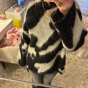 Fluffig svartvit stickad tröja - Säljer en oversized, fluffig stickad tröja i svart och vitt med coolt mönster. Tröjan har lång ärm och är supermjuk, perfekt för att mysa i under kyliga dagar. Passar dig som gillar en avslappnad och trendig stil.