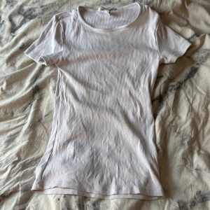 Vit ribbad t-shirt från H&M - Säljer en vit ribbad t-shirt från H&M i storlek XS. T-shirten har rund hals och korta ärmar, tillverkad i mjuk bomull som är skön mot huden. Enkel och clean design som funkar till allt. Perfekt för dig som gillar basic och stilrent.