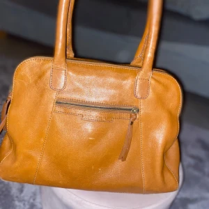 brun handväska från Stockh LM - Brun handväska från Stockholm LM passar perfekt till jobbet och skolan då den har mycket utrymme 3 fack och får plats med både dator eller mappar men även har små fack så man kan ha små saker pris går att diskutera kan mötas upp