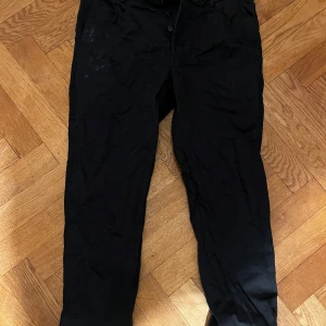 Svarta chinos med normal passform - Svarta chinos med klassisk look och normal passform. Byxorna har raka ben och stängs med knappar framtill. Perfekta för en clean och stilren outfit.