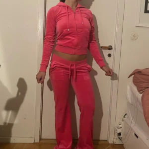 Rosa juicy couture set - Säljer ett snyggt rosa juicy couture set i mjukt velourmaterial. Byxorna har låg midja, raka ben och snörning i midjan. Fickor fram och bak med lock och knappdetaljer. Överdelen (fleecen ish) är väldigt mjuk och sitter fint. 🩷☺️