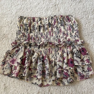 Blommig volangkjol från Zara - Kort kjol från Zara med blommigt mönster i beige, lila och svart. 