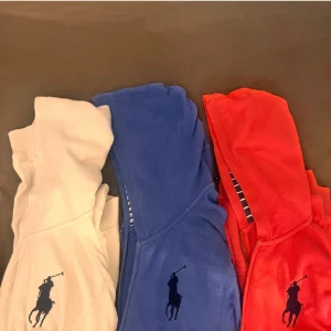 Ralph Lauren hoodie i tre färger - Säljer tre snygga hoodies från Ralph Lauren i vitt, blått och rött. Klassisk design med stor svart polospelare-logga på bröstet, dragkedja framtill, huva och känguruficka. Perfekt för dig som gillar stilren streetwear med premiumkänsla.L i barn så passar S nypris runt 1,5 styck mitt pris 370 st eller 1,1 för alla