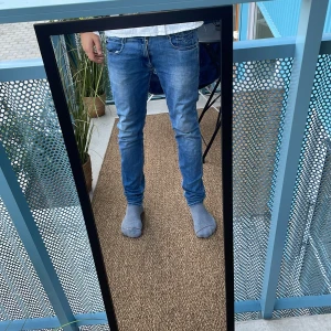 Blå slim fit jeans med slitning - Säljer ett par blå slim fit jeans med klassisk femficksdesign och snygga slitningar. Jeansen har normal midja och smal passform hela vägen ner. Materialet är mjukt denim i bomull med lite stretch för extra komfort. Perfekta för dig som gillar en modern och avslappnad look. W30 L32