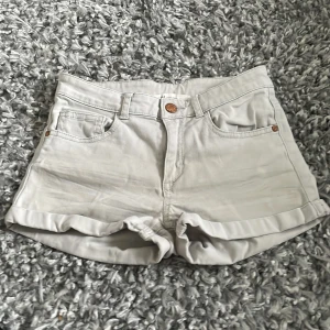 Vita jeansshorts med uppvik - Snygga vita jeansshorts med klassisk femficksdesign och uppvikta benslut. De har knapp och dragkedja framtill samt hällor för bälte. Perfekta för varma dagar och har en clean look som är lätt att matcha med allt.