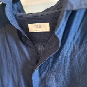 Blå linneskjorta från Uniqlo - En blå linneskjorta från Uniqlo i mycket bra skick. Säljs då den inte används. Axelbredd:42cm Längd:70cm