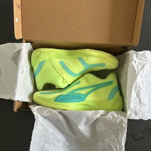 Neongula basketsneakers från Puma - Säljer ett par riktigt coola sneakers från Puma där man inte ser skosnören och själva skon är neongult med turkosa detaljer. Skorna har en modern, sportig design med rund tå och platt sula. Ovandelen är i syntetmaterial med stickade partier för extra komfort och andningsförmåga. Perfekt för dig som gillar att sticka ut. Och de är använda tre basketträningar men passade inte foten nypris 1399kr, kommer med original låda