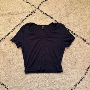 Mörkblå croppad topp från Shein  - Snygg mörkblå croppad topp från Shein i ribbad bomull. Modellen har korta ärmar och v-ringad hals, perfekt till jeans eller kjol. Enkel och stilren design som är lätt att matcha med dina favoritaccessoarer.