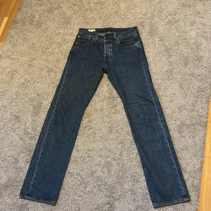 Levi's 501 Premium raka jeans blå - Klassiska Levi's 501 Premium jeans i mörkblå denim. Rakt ben, femficksmodell och ikonisk läderpatch bak. Snygg vintagekänsla och tidlös passform, perfekt till sneakers eller boots. Levi's-logga på bakfickan och robust bomullsmaterial.