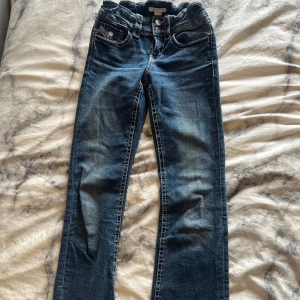 Blåa utsvängda jeans från ginatricot - Snygga blå jeans från Gina Tricot med bootcut passform och markerade kontrastsömmar. Klassisk femficksmodell, dubbla knappar i midjan och dragkedja. Jeansen har en lätt tvättad look. De är i modellen tall❣️