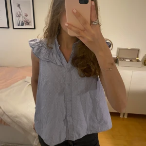 Ljusblå ärmlös blus med volangkrage - Säljer denna jätte fina blå prickiga blusen från hm. Plagget är i mycket bra skick.💕