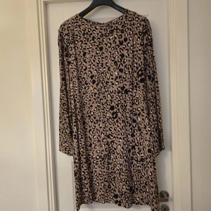 Leopardmönstrad klänning från H&M - Cool leopardmönstrad klänning från H&M i storlek XL. Klänningen har lång ärm och är tillverkad i ett mjukt, lätt material. Perfekt för dig som vill sticka ut med ett djurmönster. Färgerna går i beige, svart och brunt.