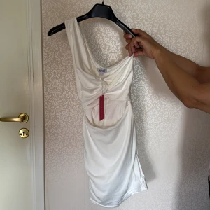 Vit klänning - Säljer en vit klänning med one shoulder och cut out i magen, den går även att knyta i ryggen till en rosett. Prislappen är kvar. Den är från en australiensk sida så den har storlek 6 som jag skulle tycka motsvarar 34-36, den kostade 600 från början 💕💕
