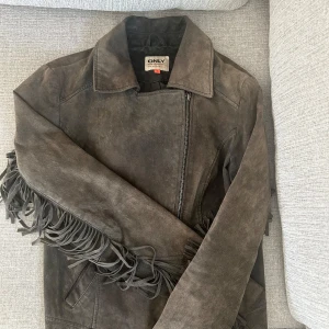 Brun läder jacka med fransar  - Säljer en brun läder jacka från ONLY med fransdetaljer längs ärmar och rygg. Jackan har dragkedja och klassisk krage, lite liten i storlek