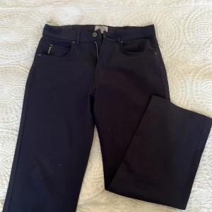 Svarta kostymbyxor från Armani Jeans - Säljer ett par svarta kostymbyxor från Armani Jeans med klassisk passform och raka ben. Byxorna har fickor fram och bak, bälteshällor och stängs med dragkedja och knapp. Perfekta för en stilren look!! Vintage! 