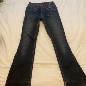 Mörkblå bootcut jeans från Reporter - Säljer ett par mörkblå bootcut jeans från Reporter med snygga slitningar och kontrastsömmar. Klassisk femficksmodell och låg midja. Perfekta för dig som gillar en retro vibe och vill ha ett par jeans med lite vidare ben.