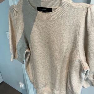 Beige stickad tröja  - Säljer en beige stickad tröja från Vero Moda med puffärmar och rund halsringning. Tröjan har ribbade muddar vid ärmslut och nederkant samt en mjuk och mysig känsla. Det finns en pytteliten fläck vid halsen som knappt syns! Skicka gärna till mig vid vidare frågor😊🫶🩷