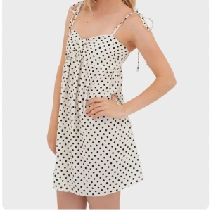 Vit kortklänning med svarta prickar - Supersöt vit kortklänning med svarta prickar och smala axelband som knyts på axlarna. Den är från meet me there och är aldrig använd. Kontakta mig om förhandling av pris! 