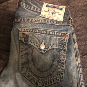 True religion jeans - Feta true religion jeans i en baggy\straight passform. Röda detaljer och hål på knäna. Midja tvärs över: 46 cm innerbenslängd: 69cm skriv vid frågor❤️