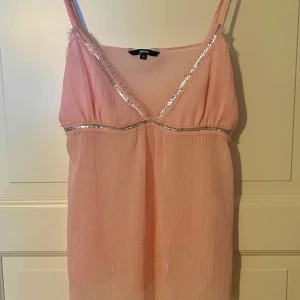 Ljusrosa Sommartopp - Säljer en ljusrosa topp från Gina Tricot med smala axelband och v-ringning. Den har jätte fina glittriga silverdetaljer 💞💞💞