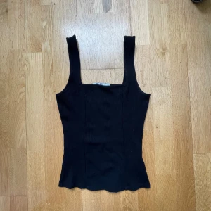 Svart ribbad linnetopp från NA-KD - Säljer en svart ribbad linnetopp från NA-KD i storlek XS. Toppen har breda axelband och fyrkantig ringning. Använd väldigt få gånger. Hör av er vid funderingar 💗