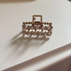 Guldig hårklämma med pärlor och stenar - En lite hårklämma i guld med små pärlor och stenar. På bild 4 ser man hur liten hårklämma är. Perfekt för att sätta undan luggen.