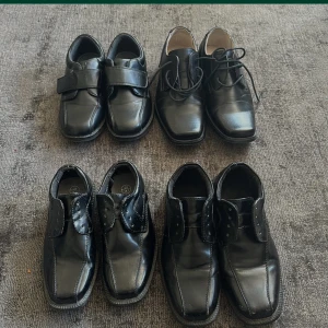 Fyra par svarta finskor - Fyra par svarta finskor i olika modeller, både med snörning och kardborreband. Skorna har rund tå och platt sula, perfekta till mer uppklädda tillfällen. Klassisk design i svart skinnliknande material.