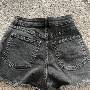 Svarta jeansshorts med fransig kant - Säljer ett par svarta jeansshorts med rå, fransig kant nertill. Perfekta för en avslappnad stil och passar till det mesta.