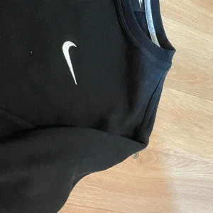 Svart sweatshirt från Nike - Säljer en svart sweatshirt från Nike med klassisk vit swoosh-logga på bröstet. Tröjan har rund halsringning och långa ärmar. Perfekt för en sportig och avslappnad stil. Storleken är L men passar S och M