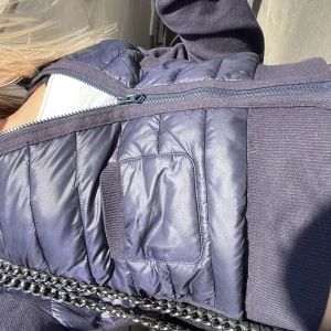 Mörkblå quiltad dunväst med dragkedja - Snygg mörkblå dunväst med quiltat mönster och dragkedja framtill. Västen har en sportig look och är perfekt att slänga över en hoodie eller tröja. Praktiska fickor på sidorna och diskreta detaljer.