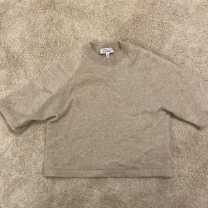 Beige stickad tröja från & Other Stories - Säljer en beige stickad tröja från & Other Stories med korta ärmar och rund hals samt en aning kort. Materialet alpacka och merinoull och väldigt skön och mjuk att ha på sig. Nypris ligger på 790kr💕