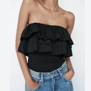 Svart volang tubtopp - Säljer en svart tubtopp med dubbla volanglager upptill. Toppen är axelbandslös och har en figurnära passform, perfekt att styla till både jeans och kjol. Materialet känns mjukt och stretchigt.☺️