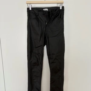Svarta bootcut skinnbyxor med dragkedja - Säljer ett par svarta byxor med bootcut-modell och dragkedja fram. Byxorna har fickor både fram och bak samt bälteshällor. Snygg passform som sitter tight upptill och släpper ut vid benslutet.