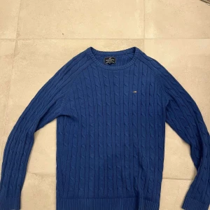 Blå kabelstickad tröja från Lexington - Säljer en blå kabelstickad tröja från Lexington i storlek M. Tröjan har lång ärm, rund halsringning och diskret logga på bröstet. Perfekt för dig som gillar klassisk och stilren design.