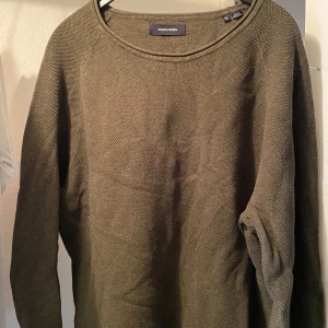 Olivgrön stickad tröja från Jack & Jones - Säljer en olivgrön stickad tröja från Jack & Jones. Tröjan har rund halsringning och långa ärmar. Perfekt för lager-på-lager och passar till många olika stilar.