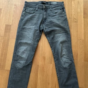 Mörk gråa anbass jeansbyxor från Replay - Snygga grå jeans från Replay med klassisk femficksdesign och raka ben. Byxorna har diskreta slitningar och svarta detaljer vid fickan med Replay-logga. Storlek: 31. Skick 9/10 däremot så saknas storleks lappen. Pris kan diskuteras!