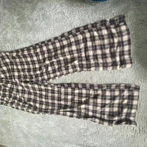 Rutiga vida pyjamasbyxor i bomull - Säljer ett par rutiga byxor med vida ben i mjuk bomull. Byxorna har elastisk midja och ett brunt och beige rutmönster. Perfekta för en avslappnad och chill stil. Skriv för fler bilder🤗