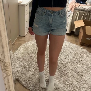 Ljusblå jeansshorts med upprullad kant - Säljer ett par ljusblå jeansshorts med hög midja och upprullad kant. De har blivit för tajta på mig. Knappt använt. Man kan rulla ihop de eller ha långa shorts
