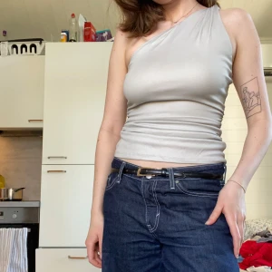 Silverfärgad oneshoulder topp - Snygg grå oneshoulder topp med en tight passform. Den är i gott skick och perfekt nu till våren och sommaren!🌸