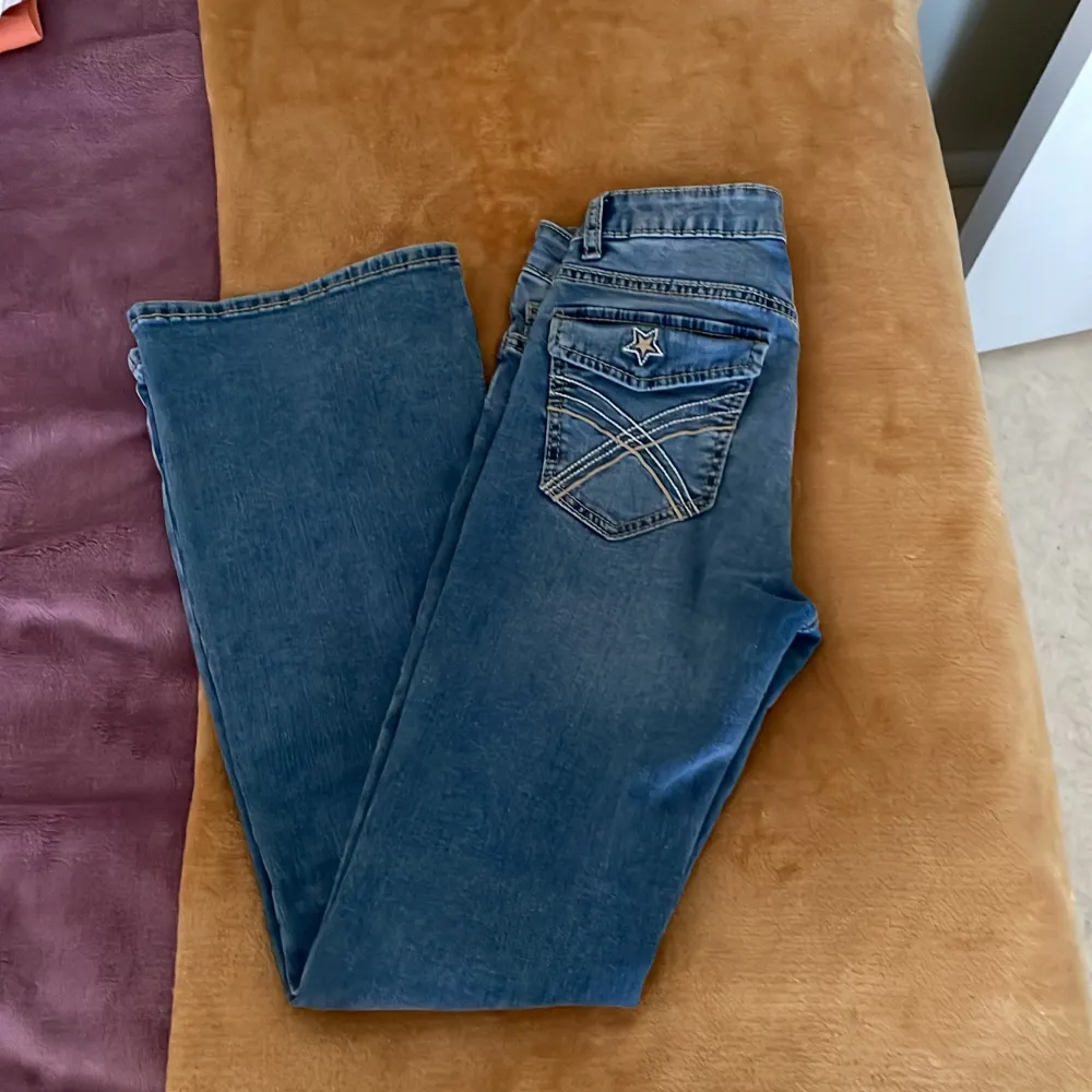Säljer ett par klassiska blå bootcut jeans från Lindex med snygga detaljer på bakfickan och normal passform. Jeansen har fem fickor och stängs med dragkedja och knapp. Perfekta för dig som gillar en tidlös stil.Nyskick!!. Farkut & Housut.