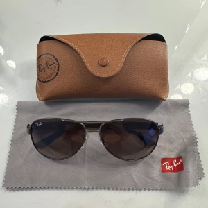 RayBan solglasögon - Snygga Ray-Ban solglasögon med klassisk pilotform och mörka linser. Bågarna är i metall med svarta detaljer och har Ray-Ban-logga på både glas och skalmar. Kommer med originalfodral och putsduk. skriv för fler bilder💕