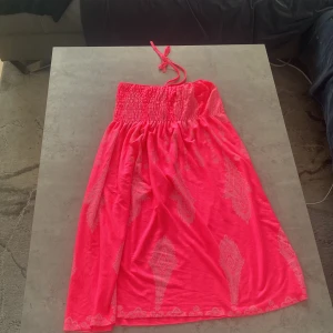 Rosa sommar klänning med mönster - Säljer en härlig rosa klänning med elastisk midja och knytband. Klänningen har ett subtilt mönster och är perfekt för varma dagar. Den är luftig och bekväm att bära.