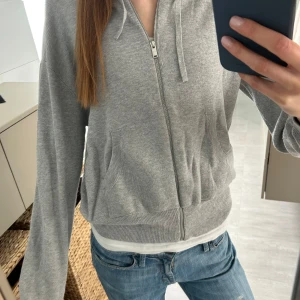Grå stickad hoodie med dragkedja - Säljer en stickad feå hoodie från H&M med dragkedja framtill och huva med snören. Gammal modell som inte säljs längre, men knappt använd så i super skick! 