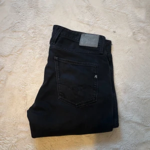  Replay jeans  - Säljer ett par svarta jeansbyxor från Replay med klassisk femficksdesign och diskreta slitningar framtill. Byxorna har normal passform och raka ben. Perfekta för dig som gillar stilrena och tidlösa jeans.