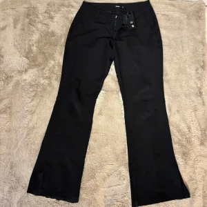 Svarta bootcut kostymbyxor från BikBok - Svarta kostymbyxor från BikBok med bootcut och slits på sidan. Perfekta till vardags eller fest! Lite slitningar vid hälen men annars bra skick!🌟