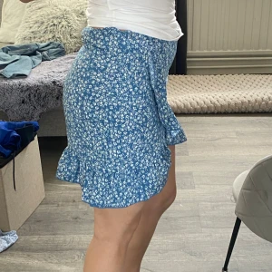 Blå blommig kjol - Söt blå kortkjol med blommigt mönster och volangdetaljer. 