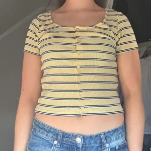 Gul och blå randig kortärmad topp - Säljer en söt gul topp från monki, knappt använd.