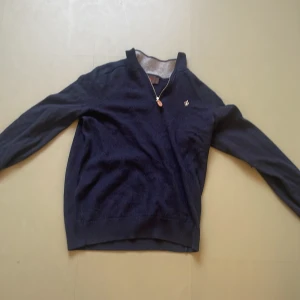 Morris half zip  - Säljer en stilren mörkblå tröja från Morris i merinoull. Tröjan har en dragkedja vid halsen och en liten broderad detalj på bröstet. Perfekt för kyligare dagar med sin mjuka och bekväma passform.